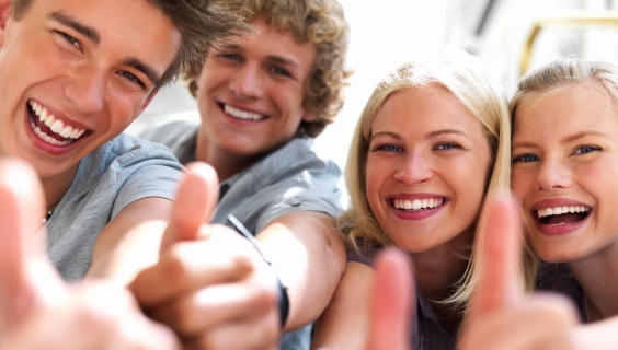 Fire smilende unge mennesker giver thumbs up